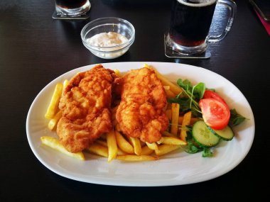 Patates kızartması, tartar sosu ve sebzeli şnitzeller, beyaz porselen bir tabakta, resim.