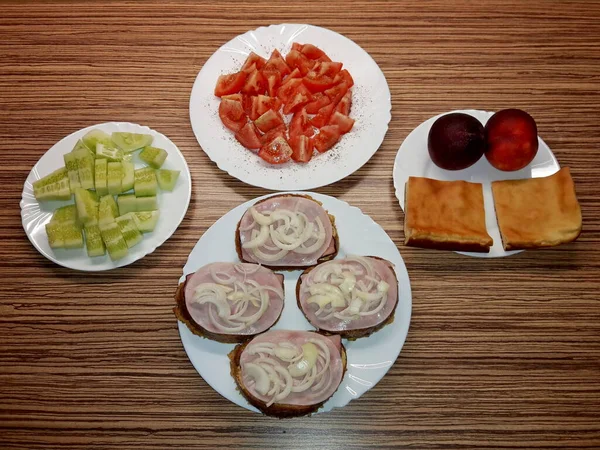 Σνακ Τέσσερα Λευκά Πιάτα Ψωμί Ζαμπόν Και Κρεμμύδι Ντομάτες Αγγούρια — Φωτογραφία Αρχείου