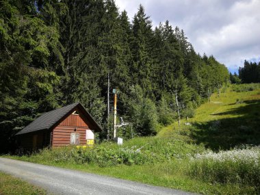 Ormanın kenarında bir kulübe, kayak pisti ve kayak asansörü, yazın görüntü.