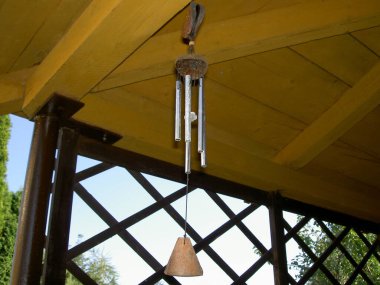 Rüzgâr çanları ahşap bir pergola asılıydı.