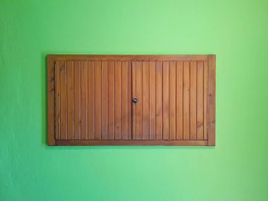 Yeşil duvarda iki yapraklı ahşap dolap.