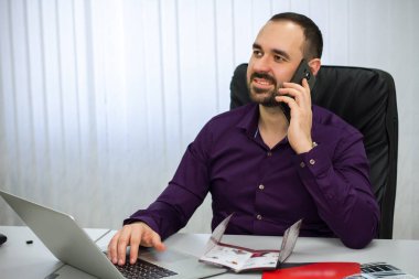 Mor tişörtlü adam office masada oturur, telefonla konuşuyor