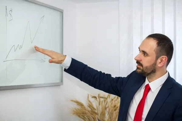 successful businessman in a suit and a red tie in the office shows a graph of profit growth