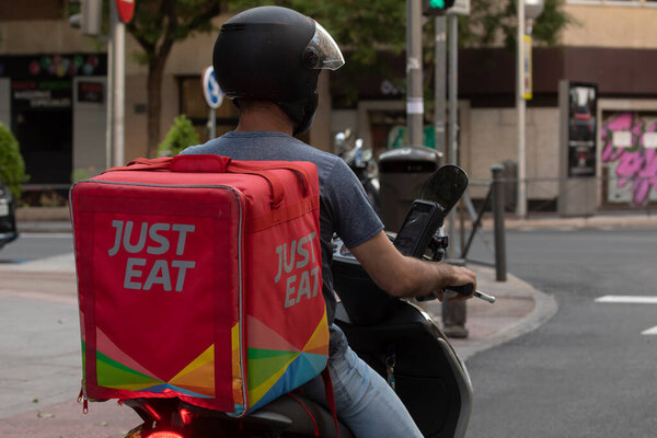 Madrid, Spain - May 19, 2020: Delivery man from the home delivery company, Just Eat, working on the streets of Madrid, delivering food at rush hour.