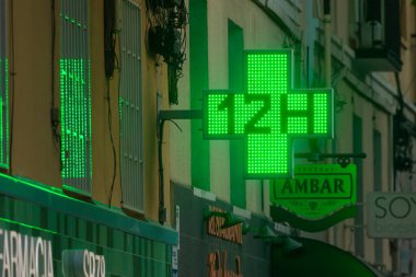 Madrid, İspanya - 19 Mayıs 2020: Retiro bölgesindeki bir eczanenin girişinde bulunan 12 H çapraz ışık işareti.
