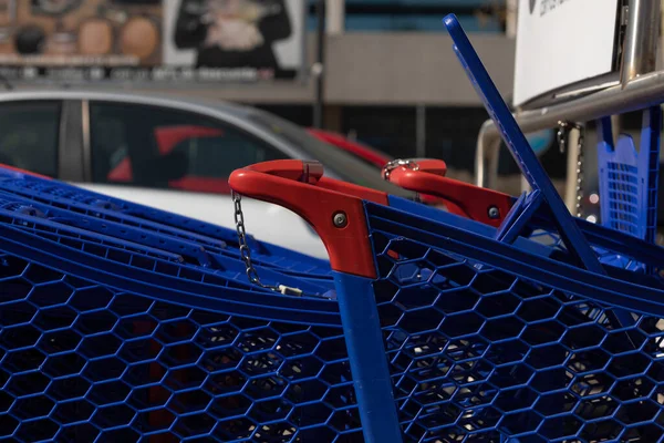 Shopping carts, blue in color and made of plastic, stored in the outdoor car park of a large shopping center, in the Ciudad de la Imagen district, Madrid, Spain.