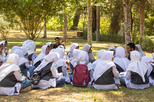 A group of veiled Muslim girls from some local school enjoy a meeting with their history teacher in the gardens surrounding the Borobudur temple in Central Java, Indonesia.