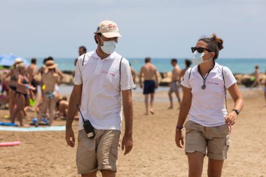 Torrenostra, Castellon, İspanya - 16 Temmuz 2020: Plaj asistanları ve görevlileri, Coronavirus salgını sırasında COVID-19 'un yayılmasını önlemek için plajda çalışmalar yapıyorlar..
