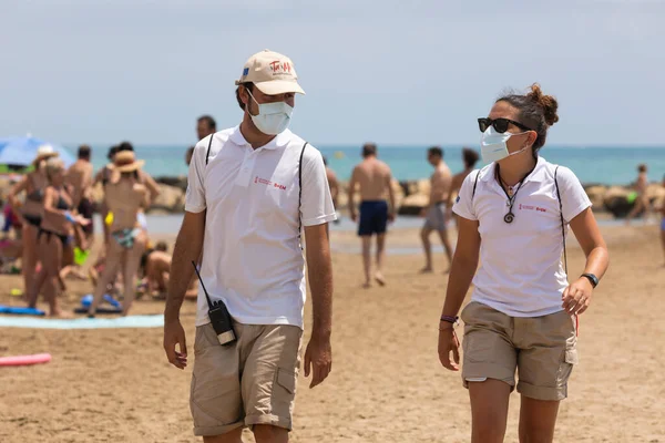 Torrenostra, Castellon, İspanya - 16 Temmuz 2020: Plaj asistanları ve görevlileri, Coronavirus salgını sırasında COVID-19 'un yayılmasını önlemek için plajda çalışmalar yapıyorlar..