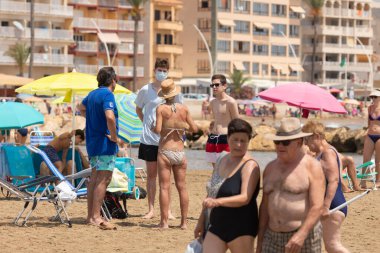 Torrenostra, Castellon, İspanya - 19 Temmuz 2020: Bir grup turist güvenlik mesafesine bakmadan ve maskesiz bir şekilde sahilde konuşuyor.
