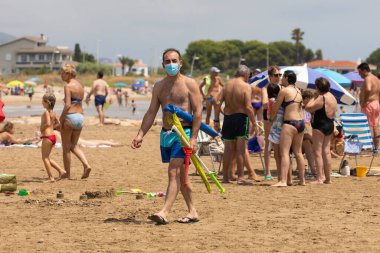 Torrenostra, Castellon, İspanya - 19 Temmuz 2020: Bir adam COVID-19 'un yayılmasını önlemek için maske takarak sahil boyunca yürür..