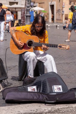 Roma, İtalya - 28 Haziran 2010: Roma 'da Piazza Navona' da gitar çalan bir sokak çalgıcısı, sadaka için çalışır ve dilenir..