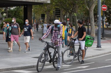 Zaragoza, İspanya - 18 Ağustos 2020: Zaragoza 'nın orta kesimindeki koronavirüs salgını nedeniyle yüz maskesi ile çalışan Glovo ve Uber Eats binicileri.