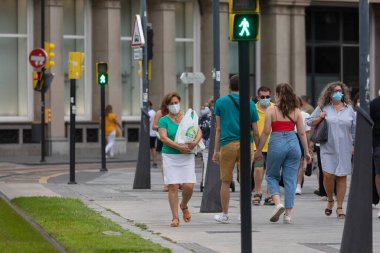 Zaragoza, İspanya - 18 Ağustos 2020: Zaragoza 'nın orta kesimindeki koronavirüs salgını nedeniyle, yüz maskeleriyle yaya geçidinde yürüyen insanlar.