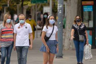 Zaragoza, İspanya - 18 Ağustos 2020: Zaragoza 'nın orta kesimindeki koronavirüs salgını nedeniyle yüz maskesi takmış bir yaya geçidinde bekleyen genç kız.