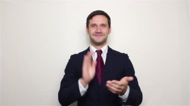 Yakışıklı genç işadamı gülümsüyor ve el çırpıyor, yeni müşterileri selamlıyor.