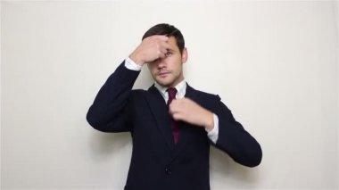 Genç yakışıklı işadamı bir mavi saçlarını penye takım elbise ve takım elbisesi, kameraya bakarak ayarlar