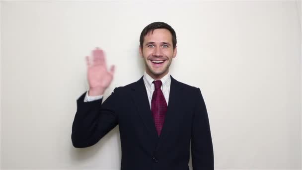 笑顔と挨拶のお客様手を振って青いスーツの若い美しいビジネスマン. — ストック動画