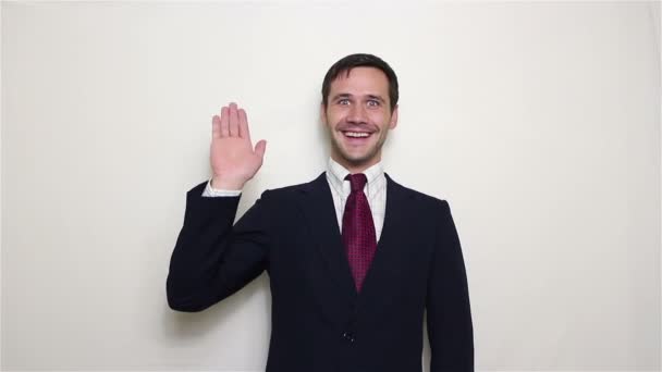 Joven y hermoso hombre de negocios en traje azul sonriendo y saludando con la mano a los clientes . — Vídeos de Stock