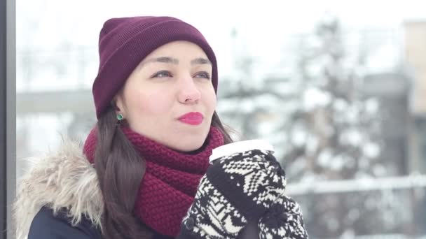 Mooi jong meisje in een romantische sfeer met plezier drinkt koffie met een rietje in een winter park. — Stockvideo