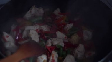 Şef bir wok tavada sebzeli tavuk baharat ekler.