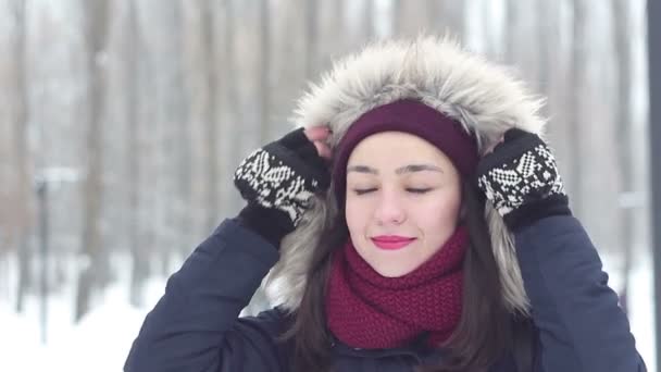 Vacker ung flicka värmer händerna med sin andetag medan promenader i skogen vinter. — Stockvideo