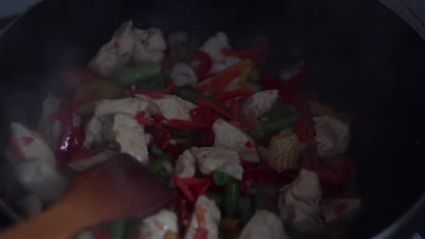 Kocken lagar kyckling med grönsaker i en wok-panna. — Stockvideo