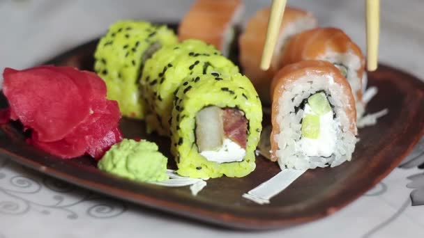 Ruka s hůlkami vezme sushi z talíře. — Stock video