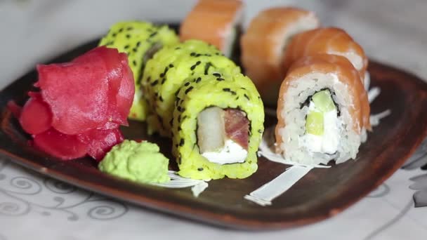 Ruka s hůlkami klade marinovaným zázvorem na desce a trvá jeden sushi rolka. — Stock video