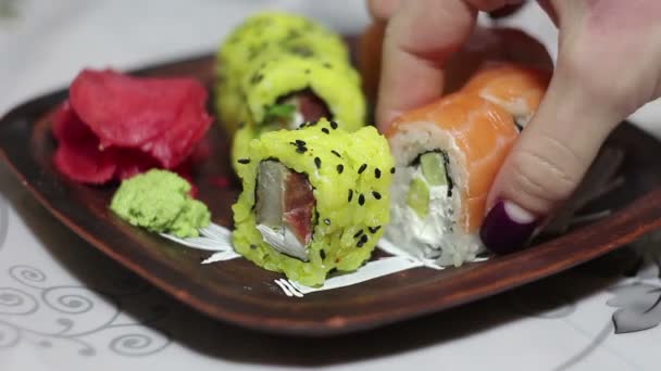 Γυναικείο χέρι παίρνει ρολό σούσι από ένα πιάτο. — Αρχείο Βίντεο