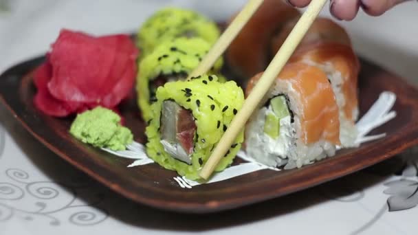 Ręka z pałeczkami trwa roll sushi z płyty. — Wideo stockowe