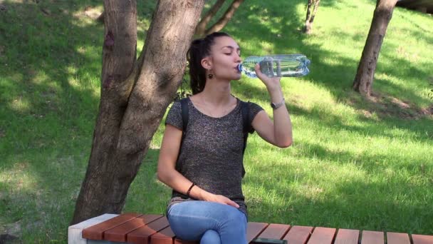 Mooi meisje opent een plastic fles met water en dranken uit haar. — Stockvideo