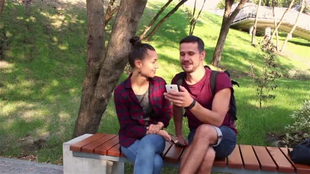 Giovani amanti si siedono su una panchina nel parco e hanno una conversazione . — Video Stock