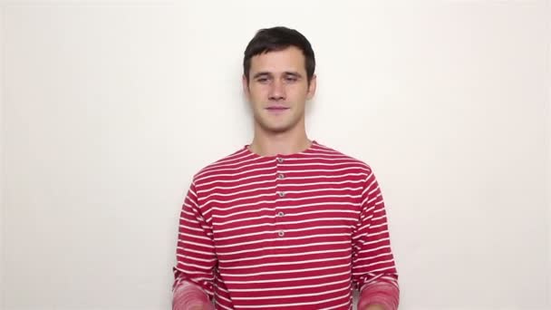 Молодой красивый парень в полосатом свитере жонглирует тремя красными яблоками . — стоковое видео