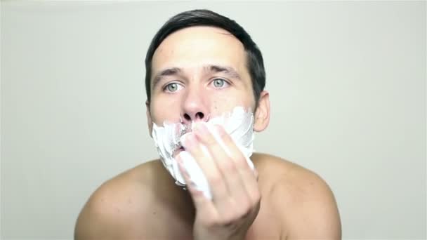 Joven chico guapo aplica espuma de afeitar . — Vídeos de Stock