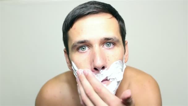 Young handsome guy applies shaving foam about to shave. — Stock Video
