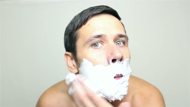 Joven chico guapo aplica espuma de afeitar a punto de afeitarse . — Vídeos de Stock