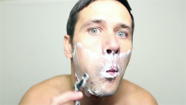 Young handsome guy shaves his face with a razor. — Stock Video