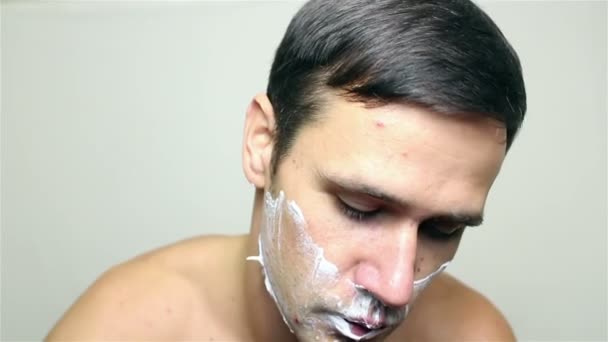 Jeune beau mec se rase le visage avec un rasoir . — Video