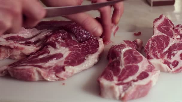 Chef-kok snijdt vers varkensvlees in steaks. — Stockvideo