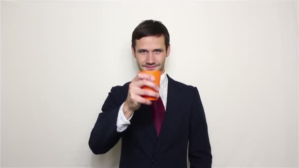 Mladý pohledný podnikatel pije z oranžová poháru. — Stock video