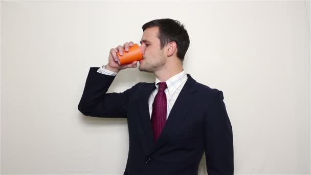 Νεαρός επιχειρηματίας όμορφος πίνει καφέ από ένα πορτοκαλί Κύπελλο. — Αρχείο Βίντεο
