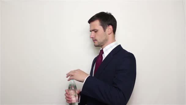 Junger gutaussehender Geschäftsmann trinkt Wasser aus einer Plastikflasche. — Stockvideo