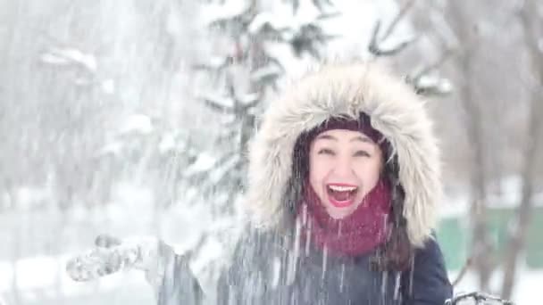 Hermosa jovencita arroja nieve con sus manos y activamente expresó alegría, ríe y aplaude sus manos . — Vídeos de Stock