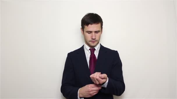 Jovem empresário bonito endireita seus botões de terno e botões nas mangas de sua camisa, olhando para a câmera . — Vídeo de Stock