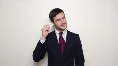 Genç yakışıklı işadamı bir dolar hışırtı için dinlemektedir. Beyaz arka plan üzerinde portre