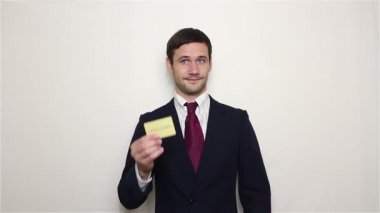 Genç yakışıklı işadamı altın kredi kartını gösterir ve parmaklarını bir kar işaret gösteren losyonları.