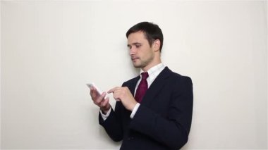 Genç yakışıklı işadamı haber aracılığıyla leafing onun Smartphone'da besleme.