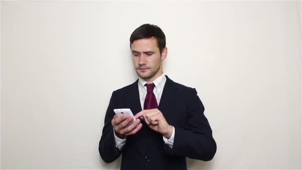 Young handsome businessman pulls out his smartphone from his pocket and looks through the news feed. — Stock Video