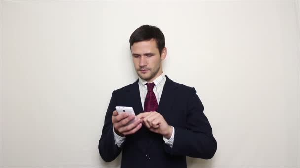 Joven hombre de negocios guapo está viendo una fuente de noticias en su teléfono inteligente. — Vídeos de Stock